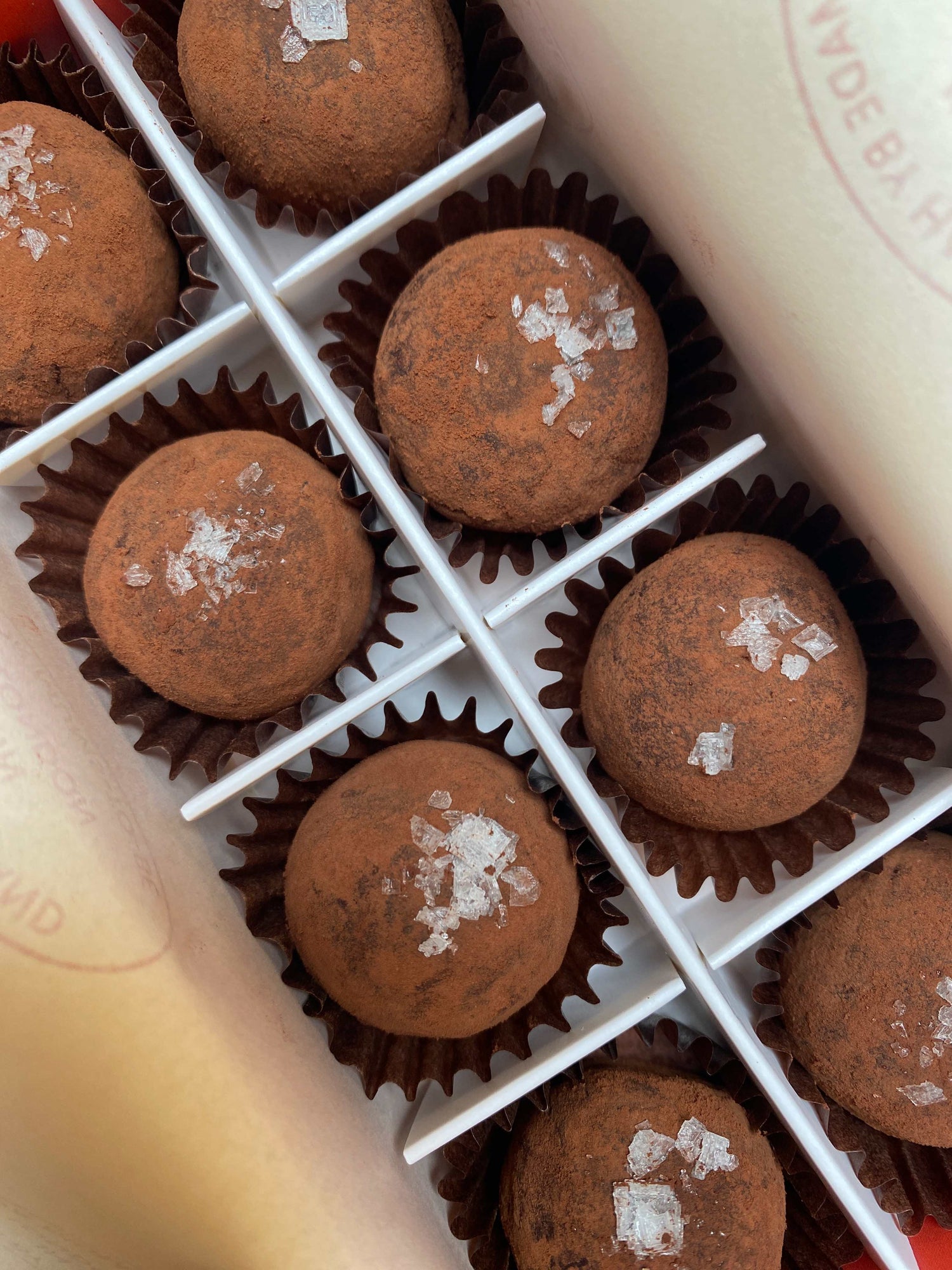 Box of chocolate truffles with sea salt on a white surface