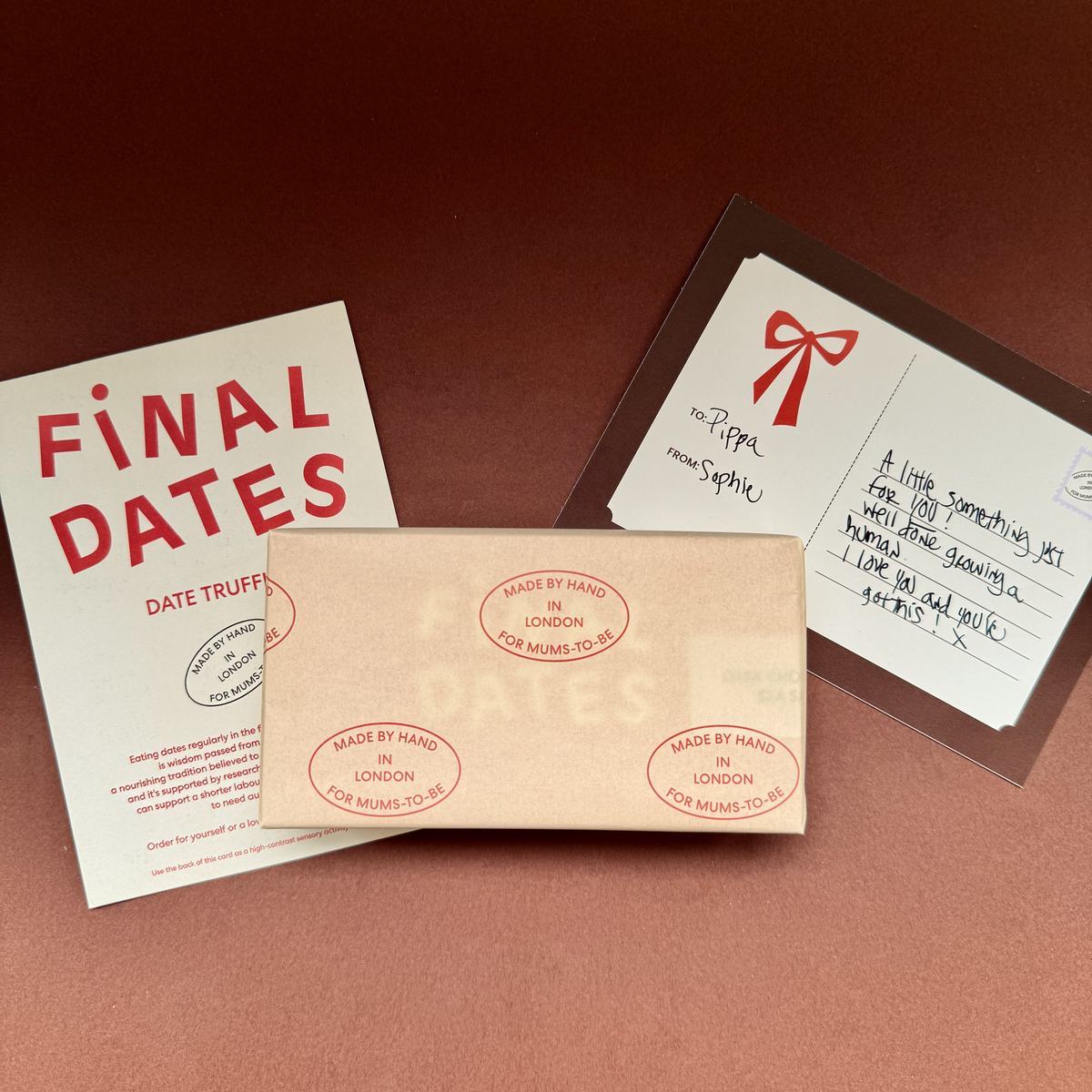 A box of gift wrapped truffles, handwritten gift card, and info card set on a warm brown background